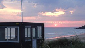 A coastal building with a flagpole, overlooking a beach at sunset.