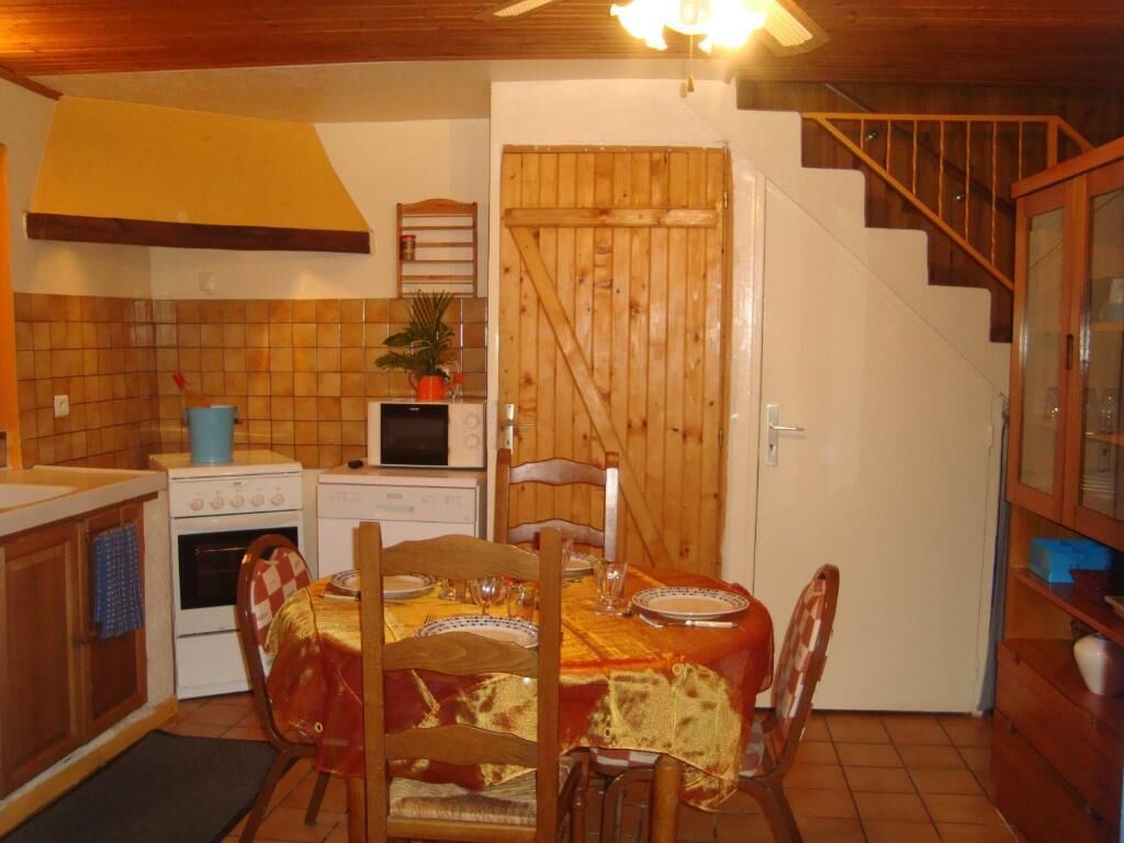 A kitchen with wooden cabinets, a stove, and a dining table set for four.