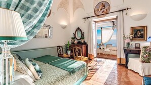 Un dormitorio con cama, cómoda, silla y vista al mar.