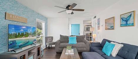 A living room with a TV, two sofas, a coffee table, and a ceiling fan.