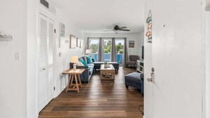 A compact living space with a sofa, coffee table, and a ceiling fan. - Salt & Sun - Beach & Pool (St. Augustine)