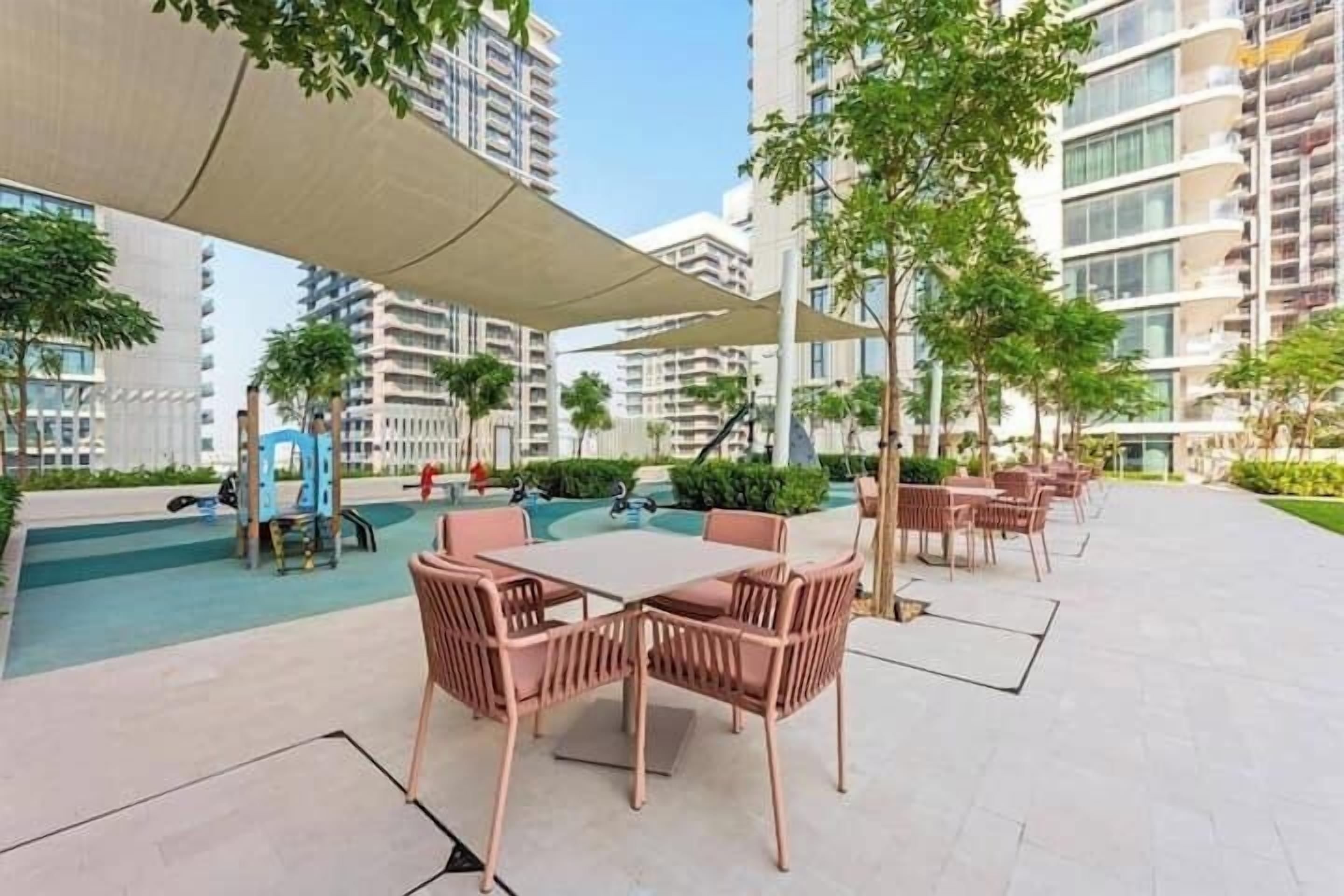 Une terrasse sur le toit avec des sièges extérieurs, une piscine et, en arrière-plan, des immeubles de grande hauteur.