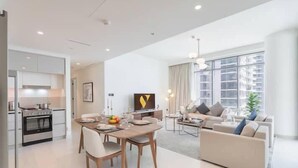A modern apartment with a dining area, kitchen, living room, and large windows.