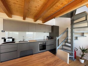 Una cocina moderna con armarios grises, una mesa de comedor de madera y una escalera en espiral.