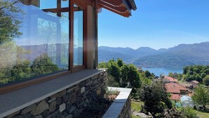 A modern house with large windows overlooking a mountainous landscape and a lake. - Rustico Milu’ (Viggiona)