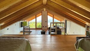 A spacious attic bedroom with wooden beams, a large window, and a balcony. - Rustico Milu’ (Viggiona)