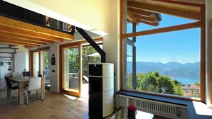 A spacious living area with a large window offering a view of mountains and a lake. - Rustico Milu’ (Viggiona)