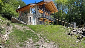 A modern two-story house with a stone foundation, wooden beams, and a balcony. - Rustico Milu’ (Viggiona)