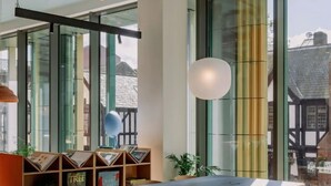 Ein modernes Interieur mit einem großen Fenster, Holzregalen, einem Tisch und Stühlen.