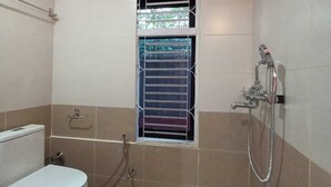 Ein Badezimmer mit Toilette, Dusche und einem Fenster mit Gitterstäben.