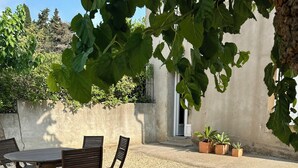 An outdoor seating area with a table and chairs, surrounded by gravel and potted plants. - Idyllic gîte with private pool and garden in beautiful surroundings. (Laure-Minervois)