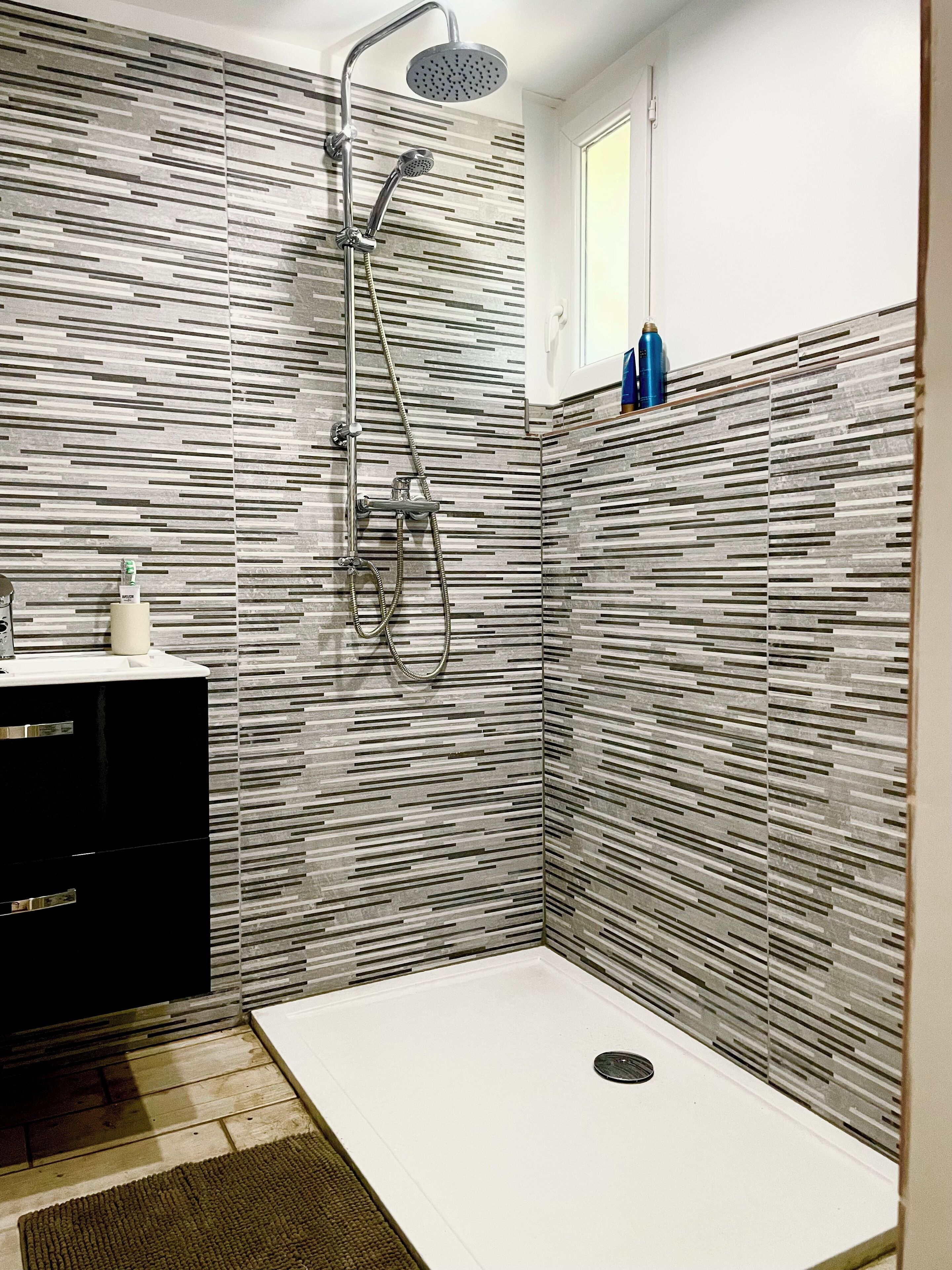 A modern bathroom with a shower, a sink, and a toilet.