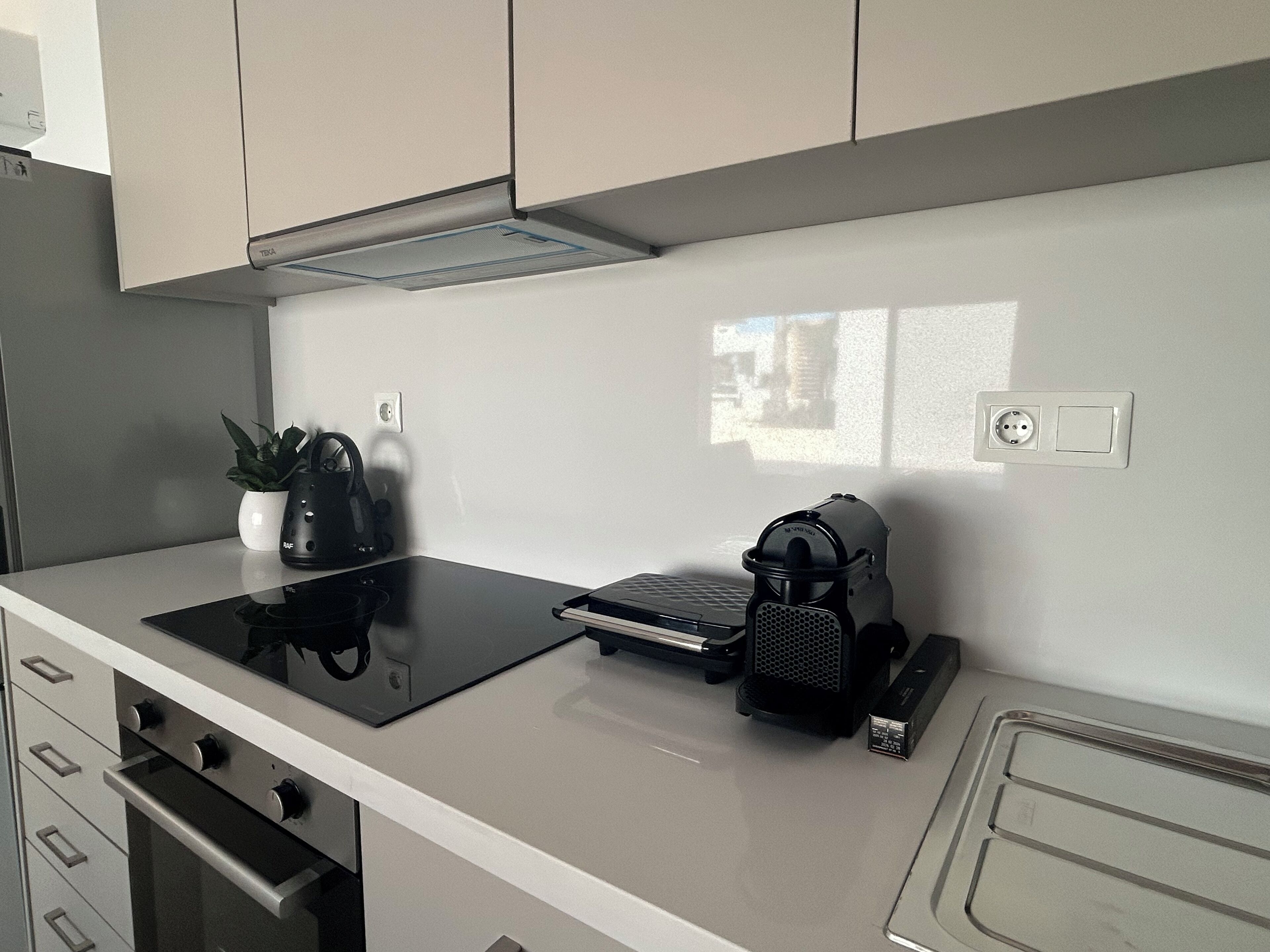 Une cuisine équipée d’une cuisinière, d’un four et d’un plan de travail sur lequel se trouvent une bouilloire et une machine à café.