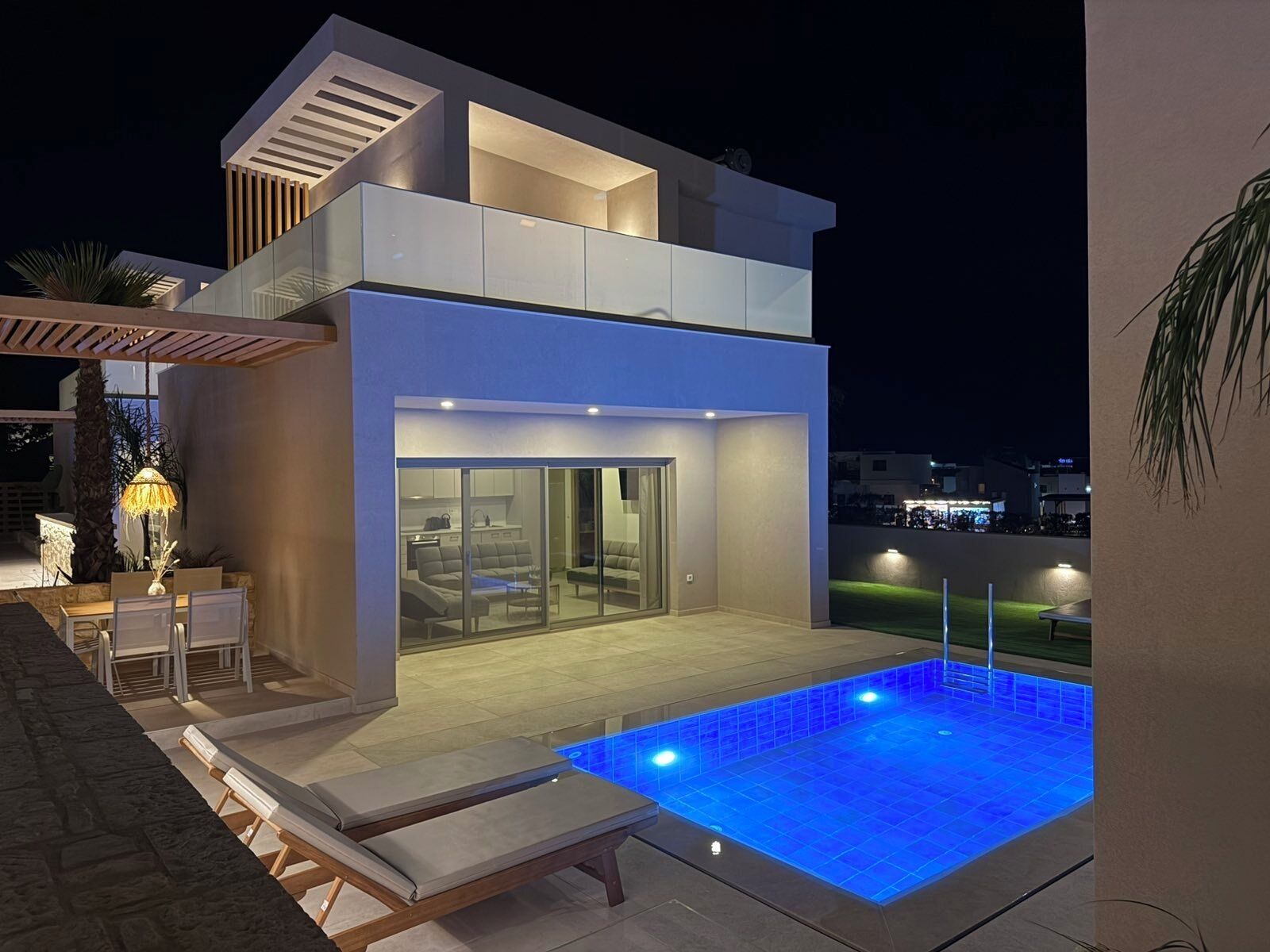 Una casa moderna de dos pisos con balcón acristalado y piscina.
