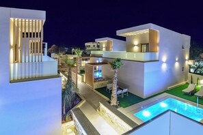 A modern residential complex with multiple buildings, a swimming pool, and outdoor seating areas. - Lumina Sense Villas (Kato Gouves)
