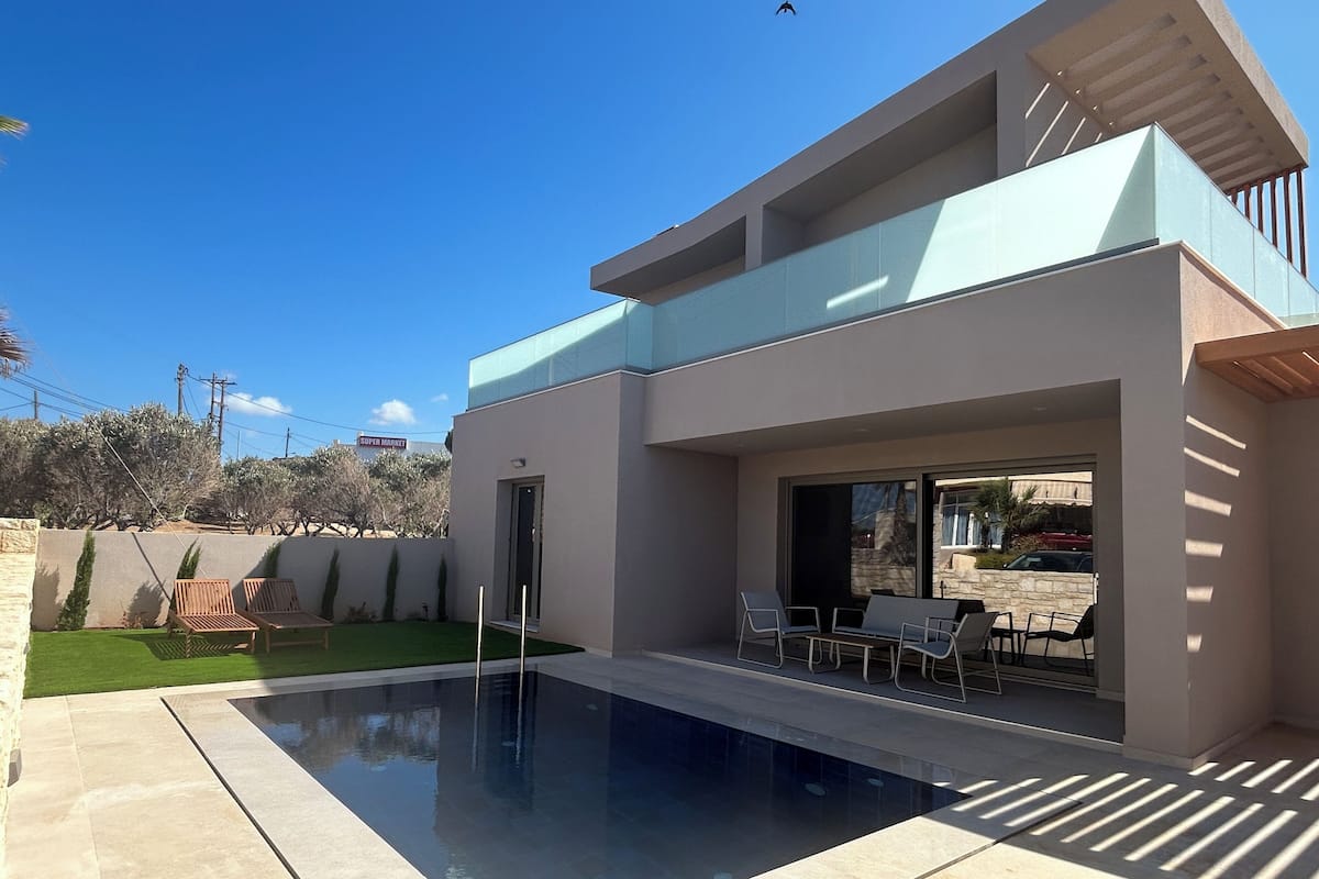 A modern house with a swimming pool, outdoor seating, and a view of the surrounding area.
