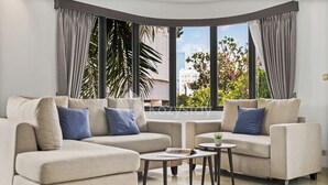 A modern living room with two sofas, a coffee table, and a view of greenery and buildings through large windows. - Beleria by Kozystay - Senayan (Jakarta)