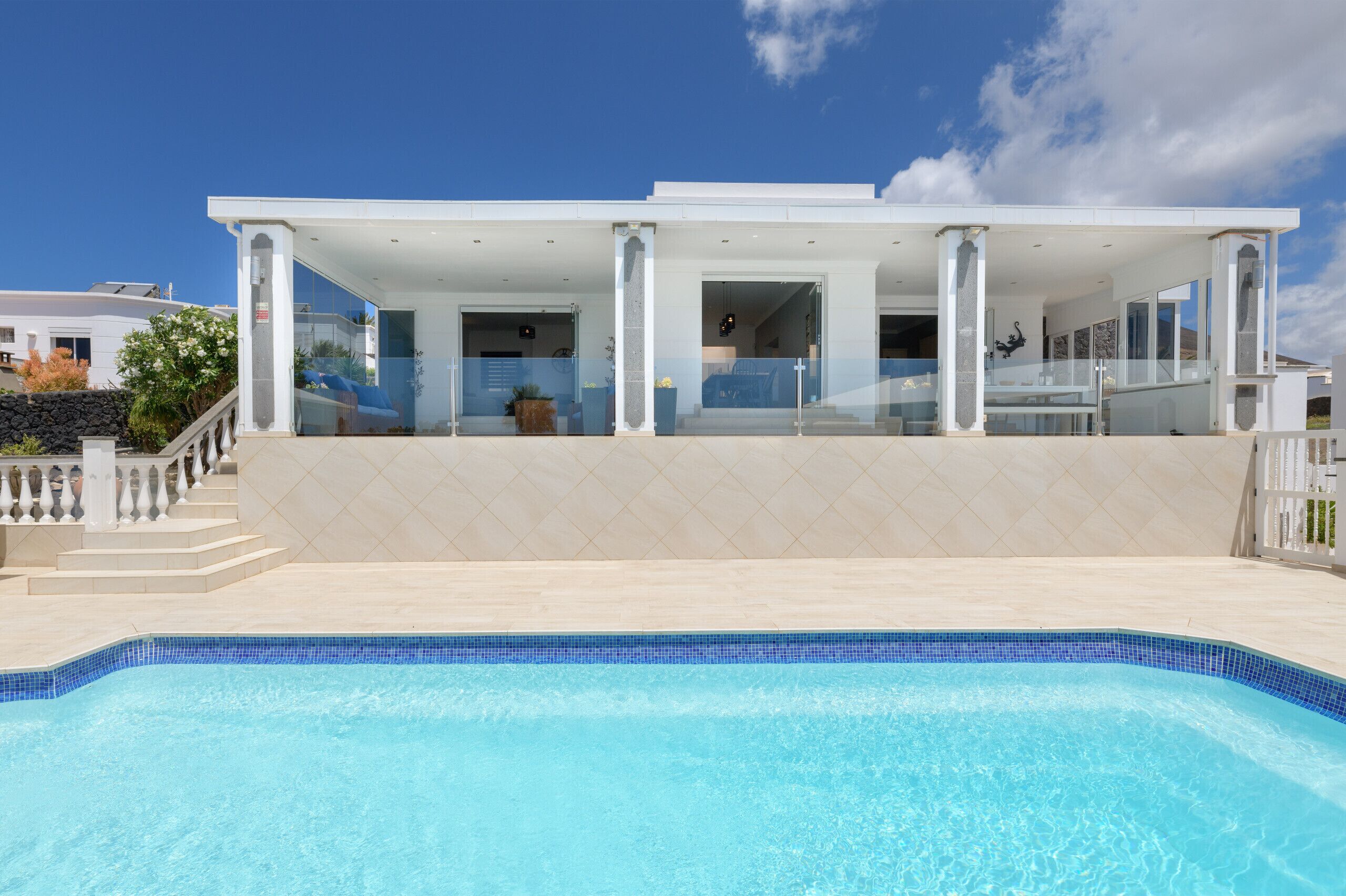 A modern house with a swimming pool, large glass windows, and a covered patio area.