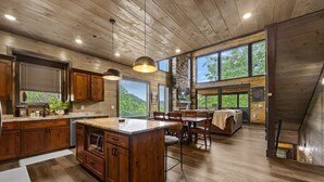 Una cocina amplia con armarios de madera, una isla grande y un comedor con chimenea de piedra.