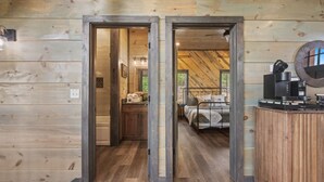 Interior de una cabaña de madera con un dormitorio, un baño y una zona de cocina.