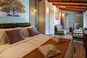 Une chambre d’hôtel avec un lit, une chaise, une table et un tableau au mur.