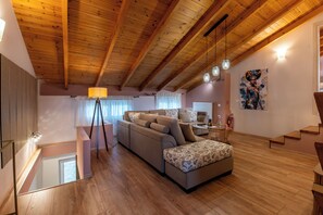 A modern living room with a wooden ceiling, a sofa, a lamp, and a painting on the wall.