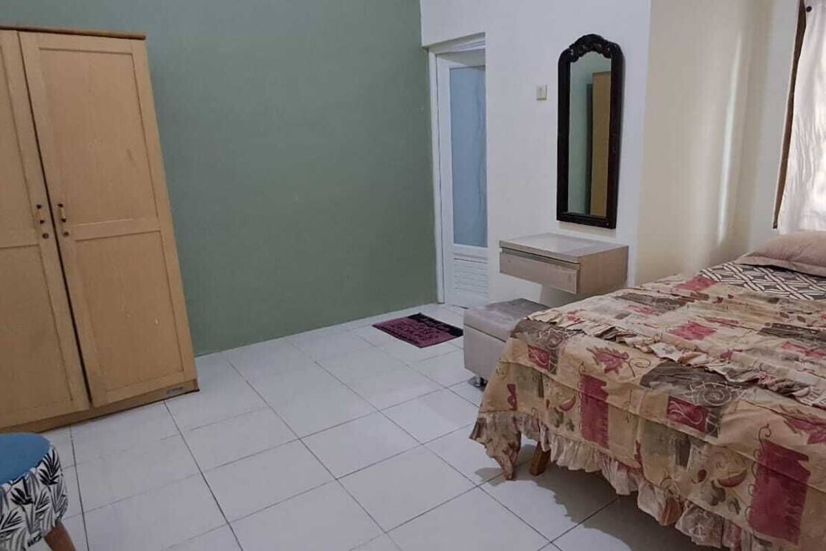 A bedroom with a bed, a wardrobe, a mirror, and a door.