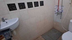 A small bathroom with a white sink, toilet, and shower. - Ventera Homestay (Kalasan)