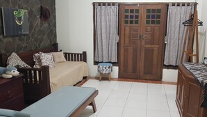 A cozy living room with a sofa, a small table, a wooden cabinet, and a television. - Ventera Homestay (Kalasan)