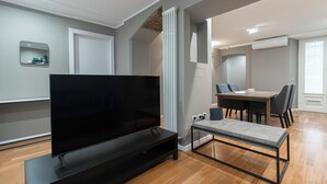 A modern living room with a flat-screen TV on a stand, a dining table with chairs, and a large window. - Italianway - Solferino 33 (Milan)
