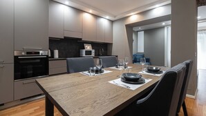 A modern kitchen with built-in appliances, a dining table set for four, and a view into the living area. - Italianway - Solferino 33 (Milan)