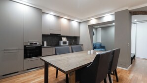 A modern kitchen with built-in appliances, a dining table with chairs, and a blue sofa in the adjacent living area. - Italianway - Solferino 33 (Milan)