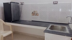 Cuina amb nevera, un rentamans i una cadira blanca.