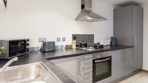 A modern kitchen with a stainless steel range hood, a built-in oven, and a black countertop. - Modern 2 Bed apartment in Liverpool, City Centre (Merseyside)