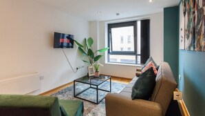 A living room with a sofa, a coffee table, a TV, and a window. - Modern 2 Bed apartment in Liverpool, City Centre (Merseyside)