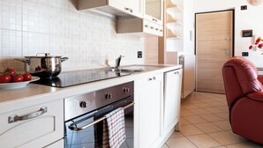 Une cuisine moderne avec des meubles blancs, un évier en acier inoxydable et un four encastré.