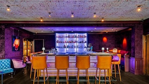 A bar with a central counter, multiple shelves of bottles, and bar stools. - Luxury apartment with balcony, free SPA use and gym (Sylt)