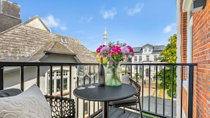 A balcony with a table, a vase of flowers, and a bottle of wine. - Luxury apartment with balcony, free SPA use and gym (Sylt)
