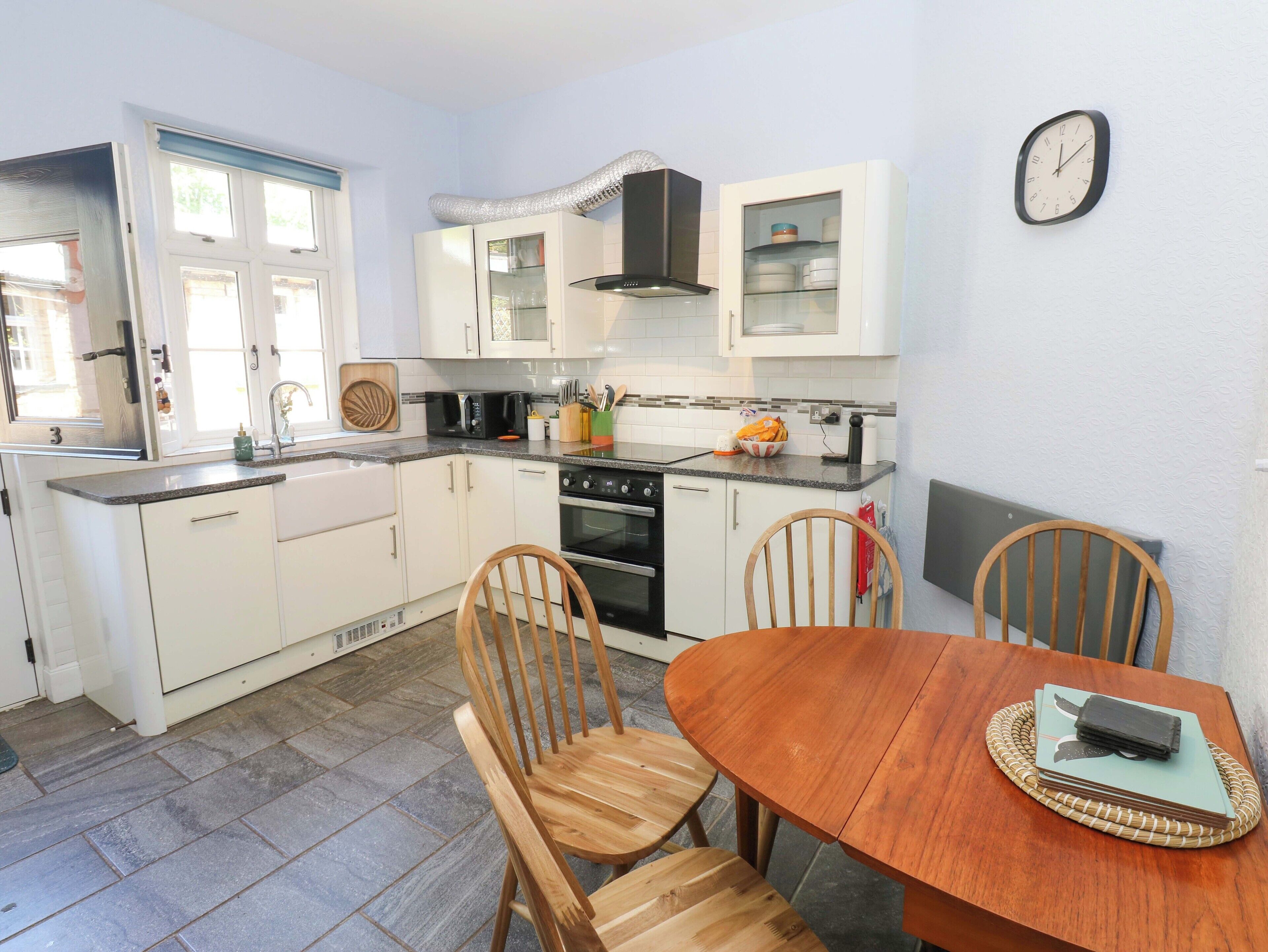 A compact kitchen with white cabinets, a stove, and a dining table with chairs.