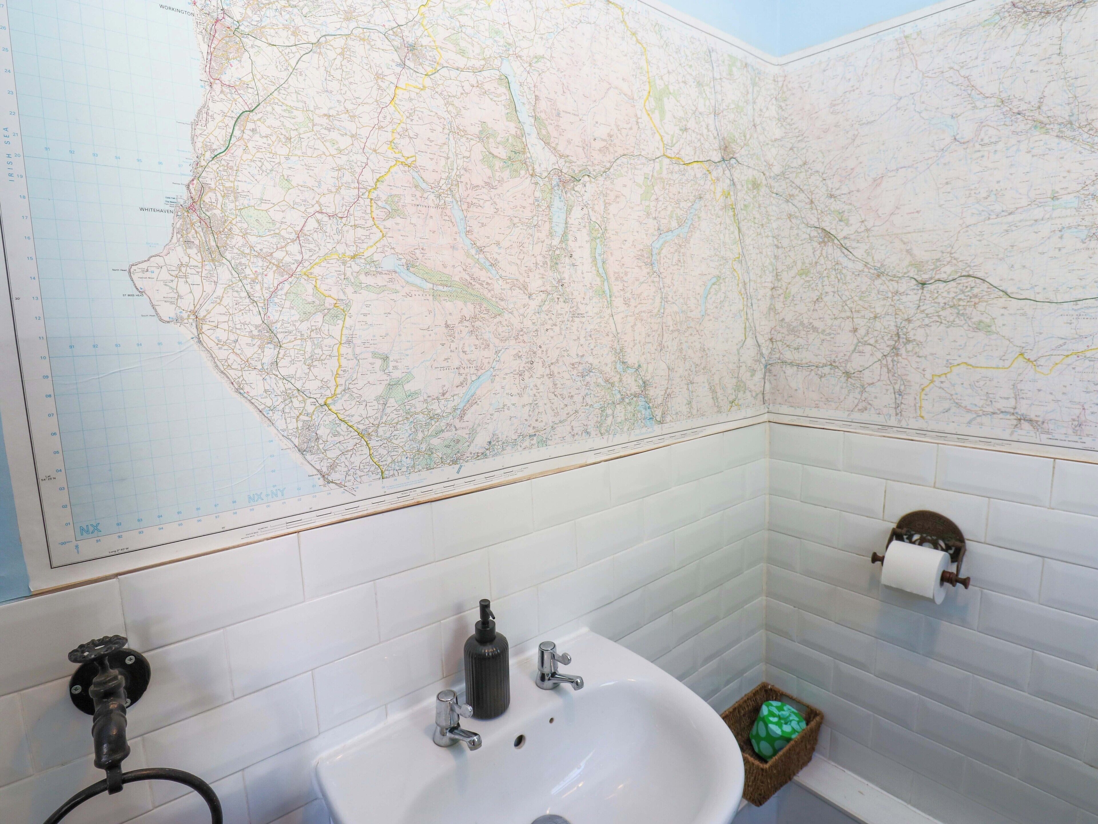 A bathroom with a map on the wall, a sink, and a toilet paper holder.