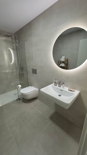 A modern bathroom with a toilet, bidet, and sink.