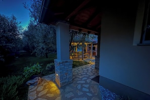 A stone pathway leading to a covered outdoor seating area with a table and chairs.