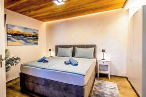 Un dormitorio con cama, mesitas de noche, un cabecero, un cuadro y techo de madera.