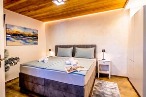 A bedroom with a bed, bedside tables, a lamp, a painting, and a wooden ceiling. - Casa Oliva Kim Marie /w Garden (Medulin)