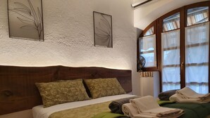 A neatly made bed with a green and gold bedspread, two pillows, and a folded white towel on the side. - In the capital of the Langhe cottage with pool and garden (Ricca)