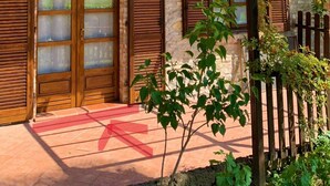A rustic building with wooden shutters, a balcony, and a tiled patio. - In the capital of the Langhe cottage with pool and garden (Ricca)
