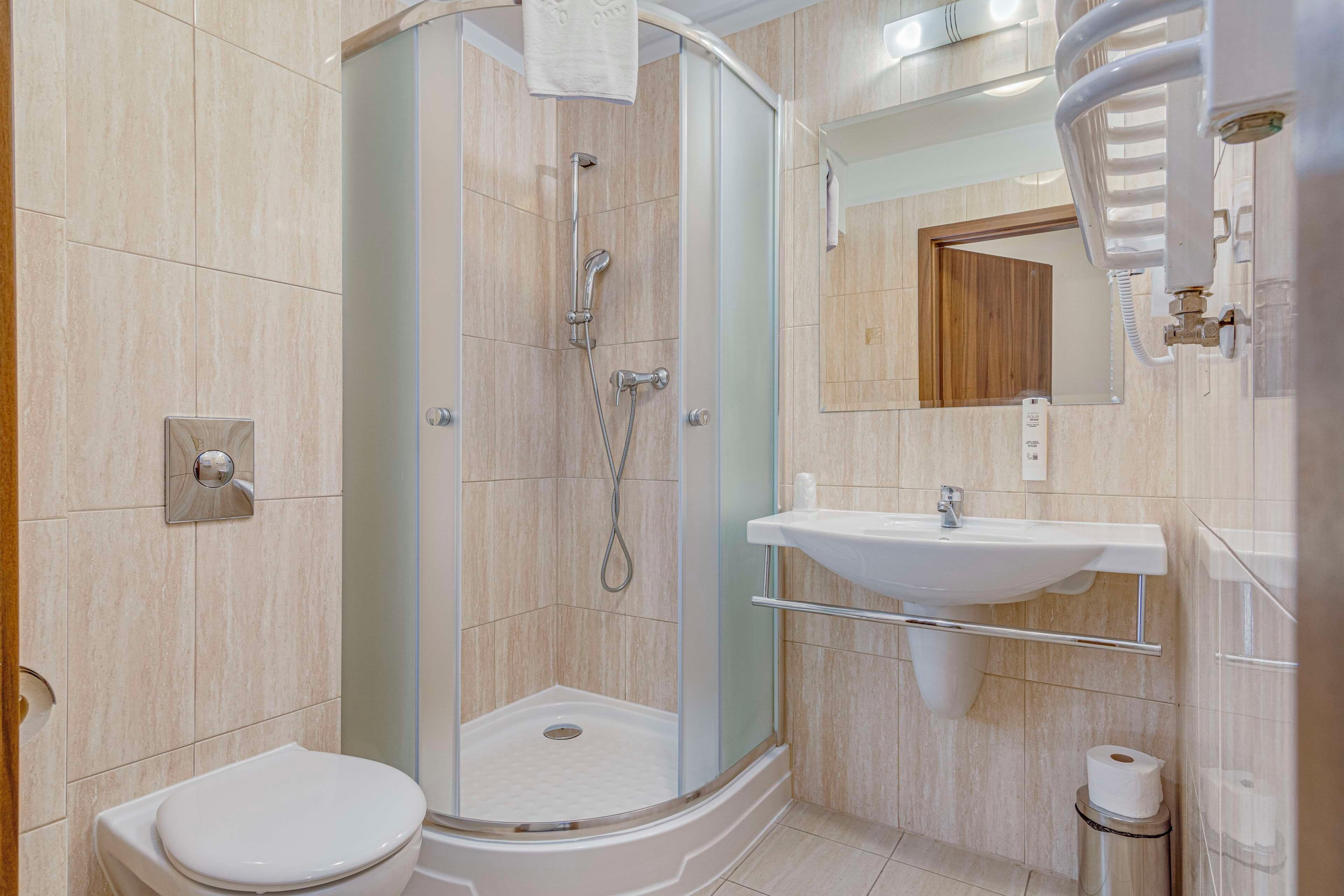 Un baño moderno con ducha envuelta en cristal, un lavabo blanco y un inodoro.