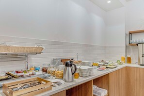Montaje de bufé con diferentes opciones de comida, una cafetera y una cesta de mimbre.