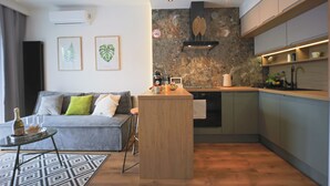 Een moderne keuken met een centraal eiland, een grijze bank met kussens en een kamerbreed tapijt met een patroon.