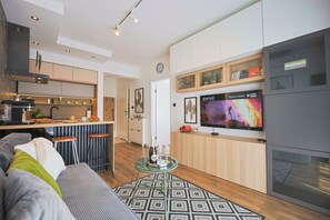 Eine moderne Küche mit Bar, einem Esstisch mit Stühlen, einer Couch und einem Fernseher.